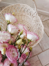 Pink and white lisianthus flowers arranged in a woven flower basket on a tiled surface; reference for Luma's basket. Photo: elena_ sher / Pexels. Reference image; final flowers and wrap subject to florist confirmation.