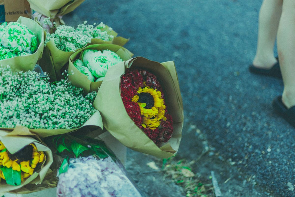 Multiple paper-wrapped bouquets in a street display; illustration of the planned three-bouquet package, not exact final set. Photo: Toàn Văn / Pexels. Reference image; final flowers and wrap subject to florist confirmation.