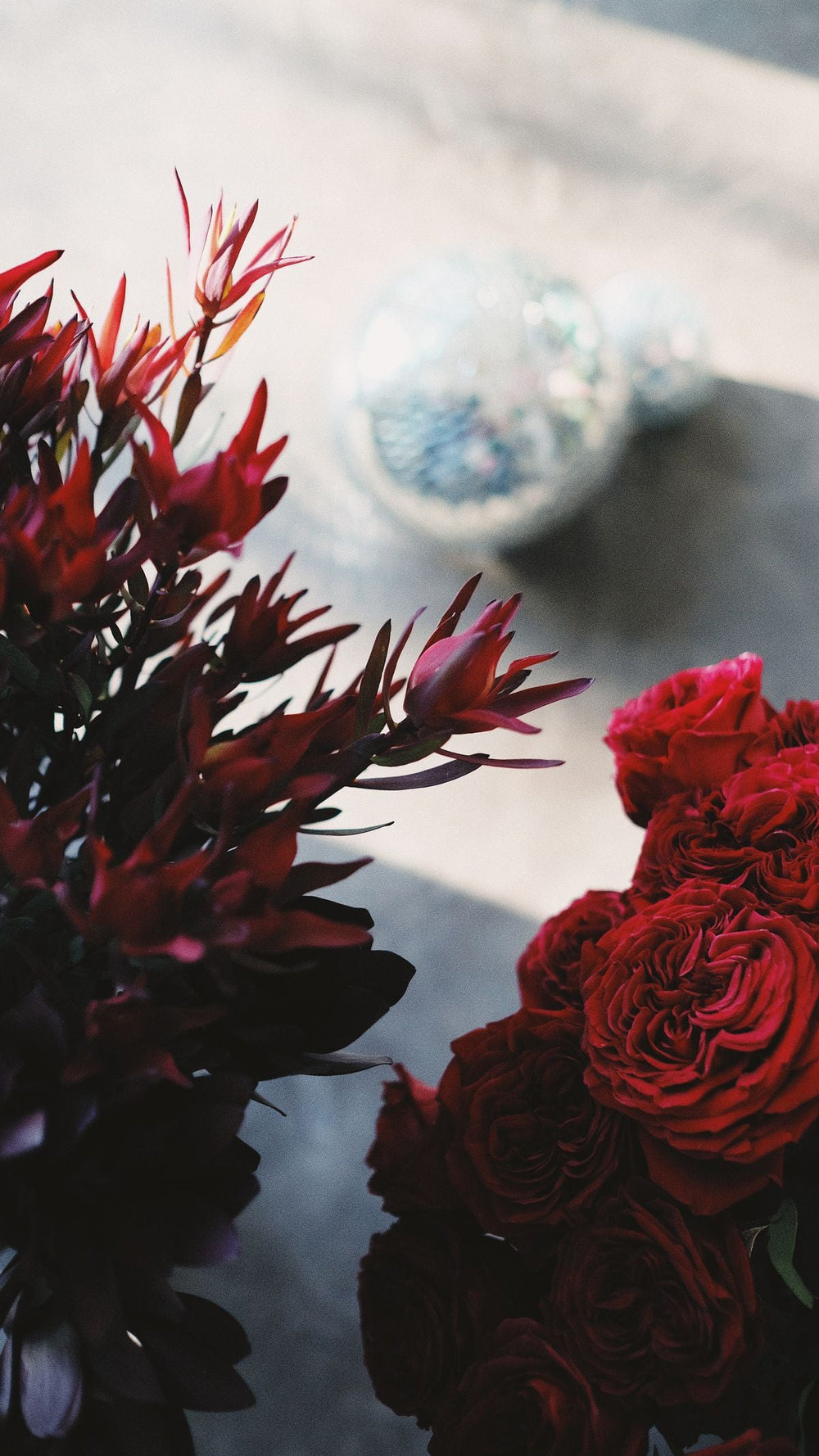 Two coordinated red flower bouquets in a natural interior; reference photo for proposed rose pair. Photo: Nadezhda Moryak / Pexels. Reference image; final flowers and wrap subject to florist confirmation.