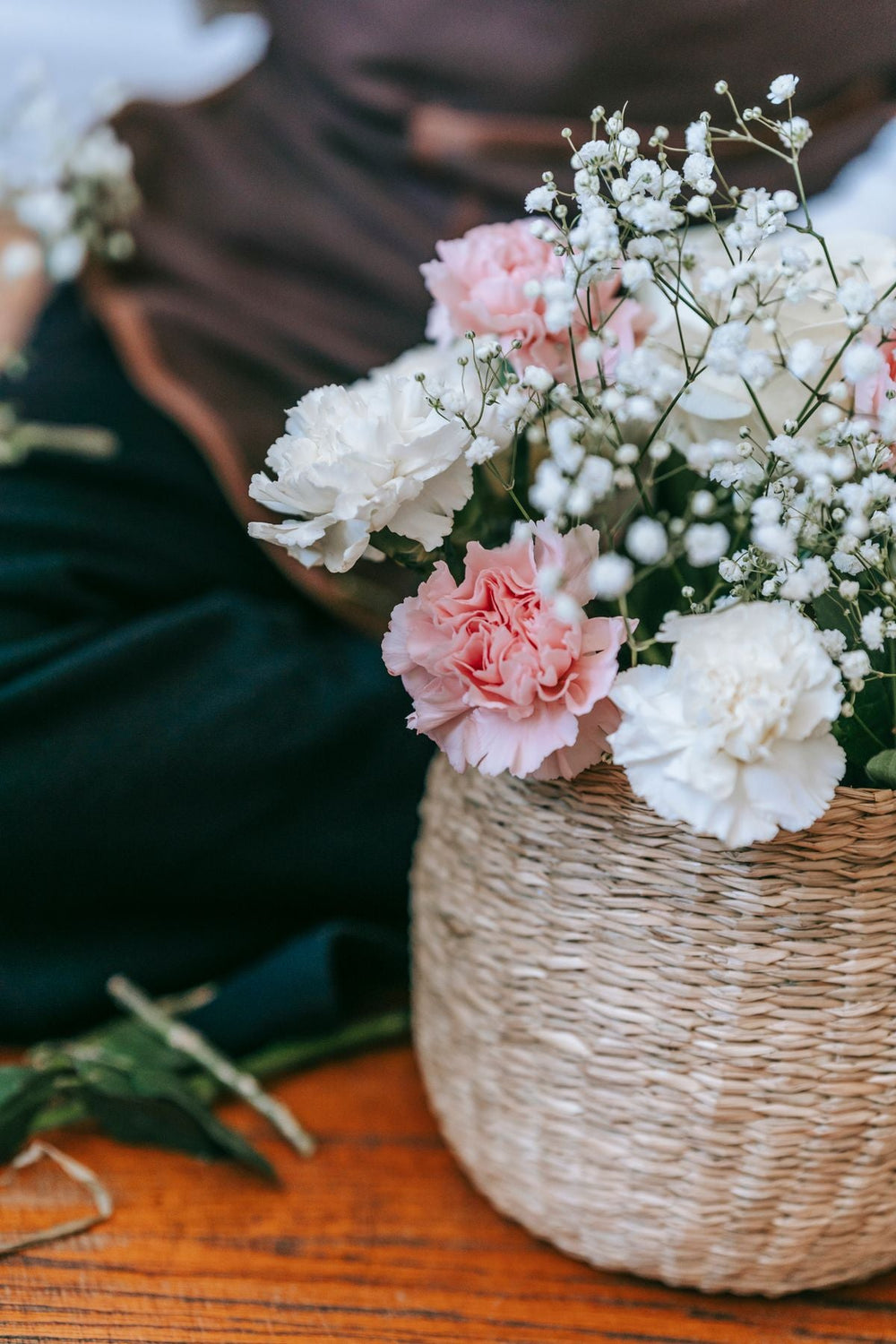 White roses and seasonal chrysanthemums arranged in a wicker basket in a natural interior; reference for proposed Luma basket. Photo: Teona Swift / Pexels. Reference image; final flowers and wrap subject to florist confirmation.