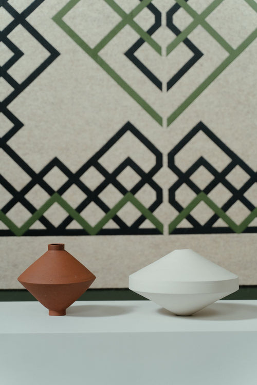 Minimalist ceramic containers in a pale white studio setting; category illustration, not the exact 19 cm charcoal cylinder. Photo: cottonbro studio / Pexels.