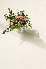 Fresh seasonal flowers in a clear vase on a white background; home-flower arrangement styling example. Photo: Polina Tankilevitch / Pexels.