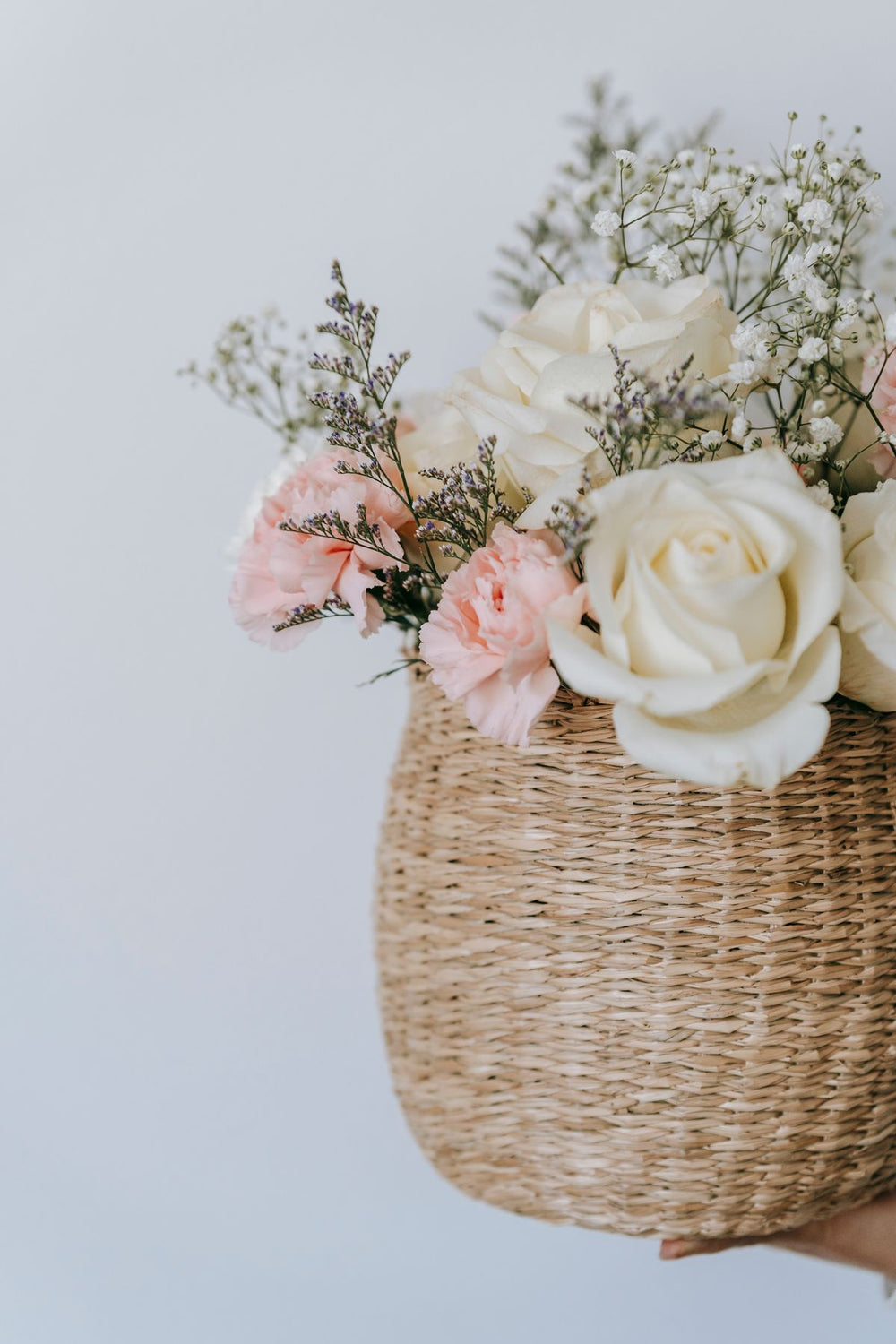 Roses and seasonal flowers in a wicker basket on a white background; reference to floral basket presentation, not exact Luma basket. Photo: Teona Swift / Pexels.