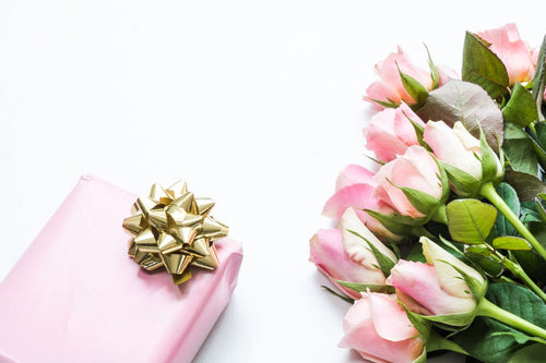 Pink roses beside a pink gift box on white; gift styling reference only, not roses arranged inside the actual Luma floral gift box. Photo: Ylanite Koppens / Pexels.
